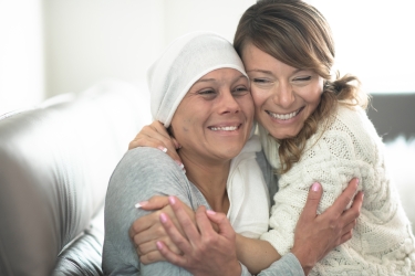 Oncology patient and friend hugging and smiling