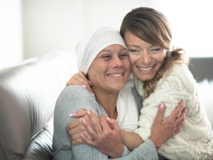 Oncology patient and friend hugging and smiling